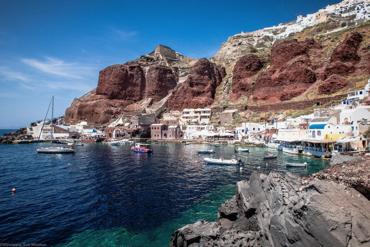 Boats anchored in the tiny harbour of Ammoudi Bay below Oia on a Santorini boat tour, Greece