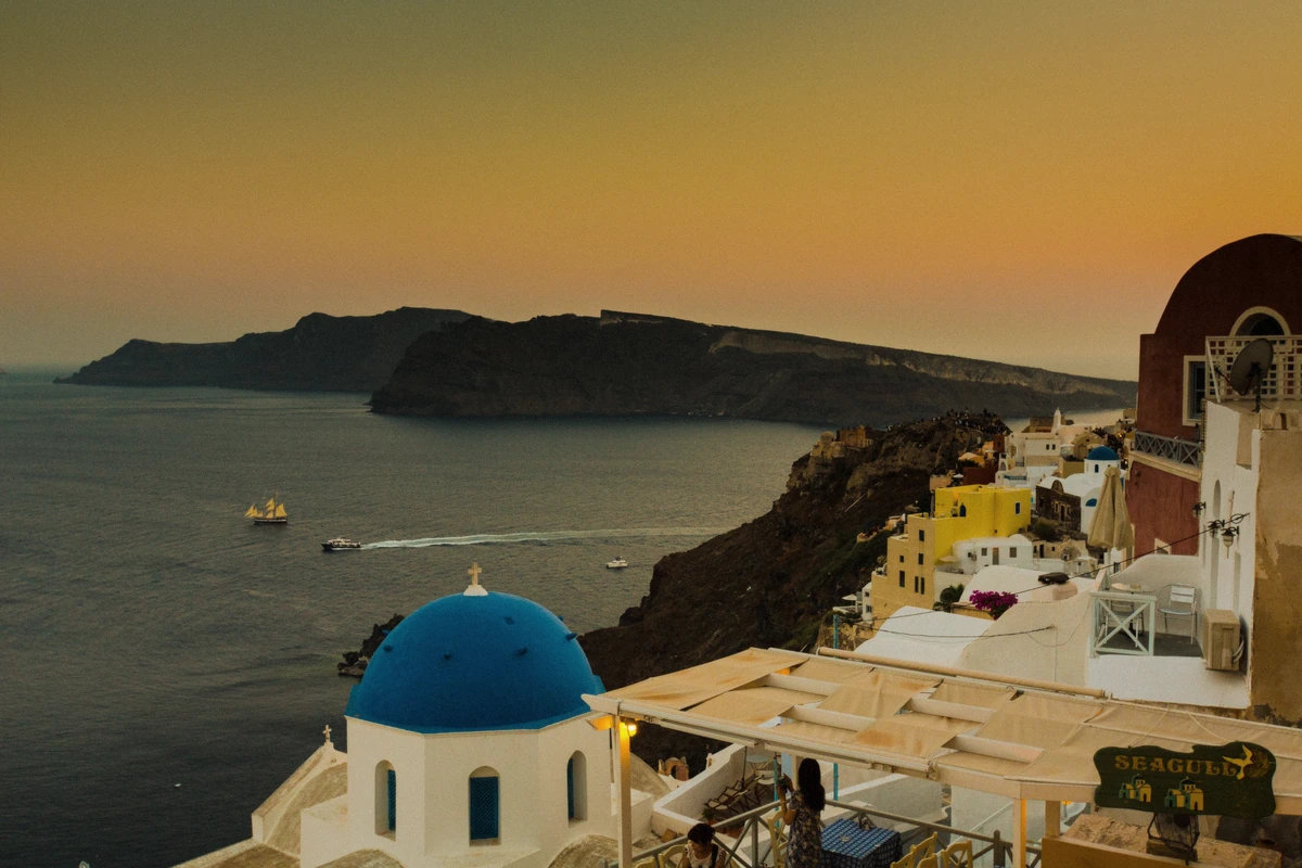 Sunset over the caldera and the clifftop town of Fira seen from a Santorini luxury sunset cruise, Greece