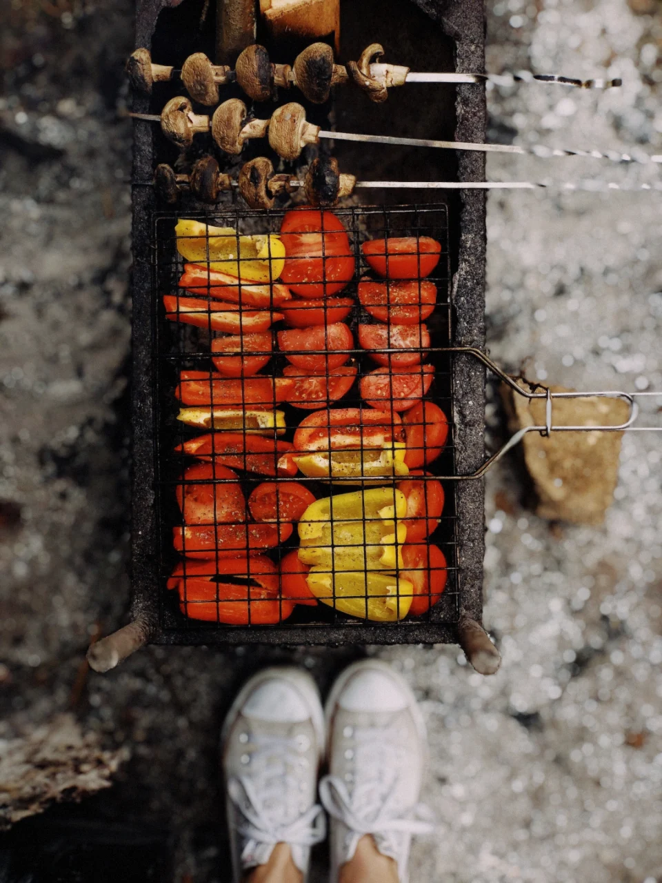 Souvlaki skewers and vegetables grilling over charcoal for a meal served on a Santorini boat tour, Greece