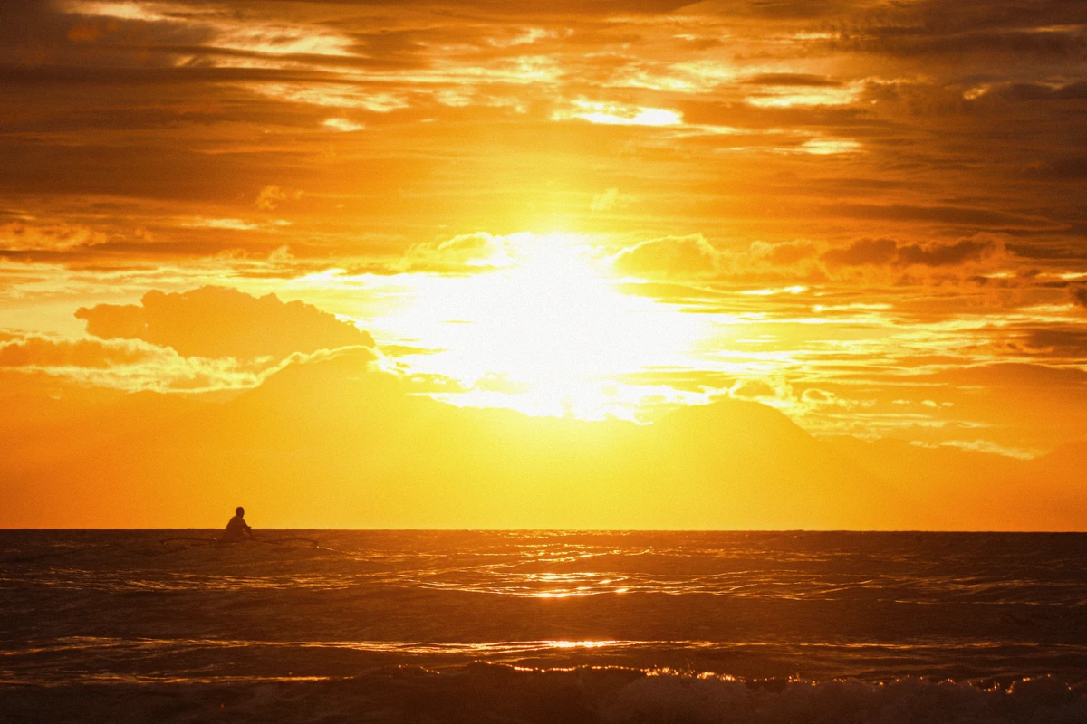 The last light over the Aegean with a lone swimmer in the water during a Santorini sunset boat tour, Greece