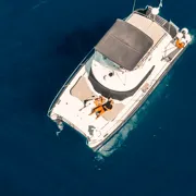 Private power catamaran anchored in a quiet caldera cove during a private Santorini boat tour, Greece